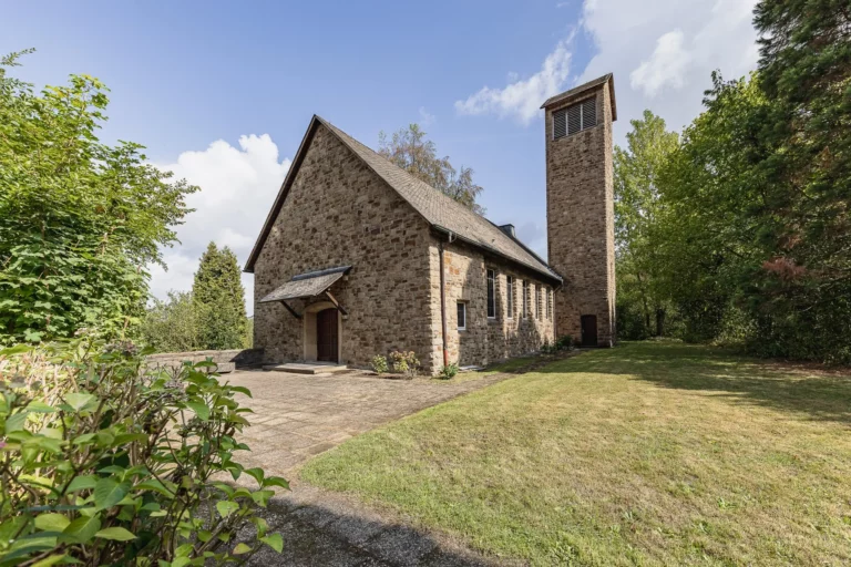 Besonderes Ensemble auf kirchlichem Grund: Kirche, Pfarrhaus und Freifläche in grüner Umgebung